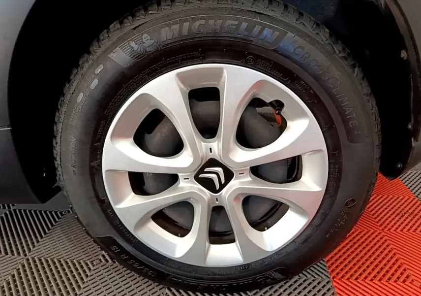 Gros plan sur la roue avant gauche d'une Citroën C3 blanche avec jante alliage et pneu Michelin CrossClimate.