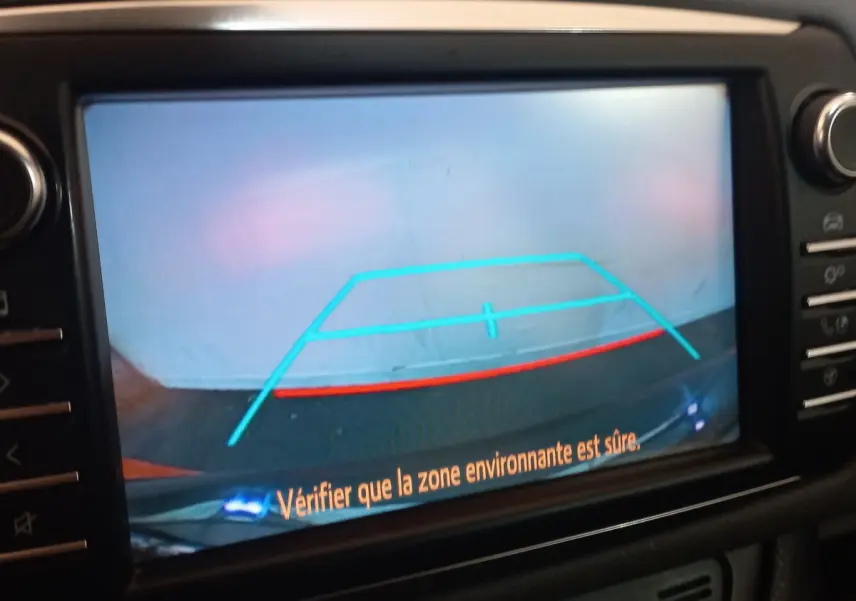 Écran tactile intérieur affichant la caméra de recul de la Toyota Yaris hybride noire avec repères de stationnement colorés.