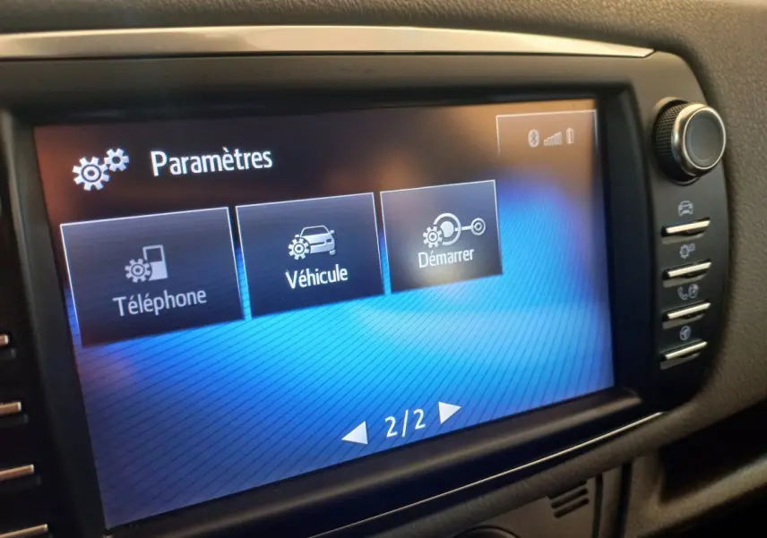 Écran tactile central affichant le menu paramètres dans l'habitacle d'une Toyota Yaris noire, vue rapprochée.