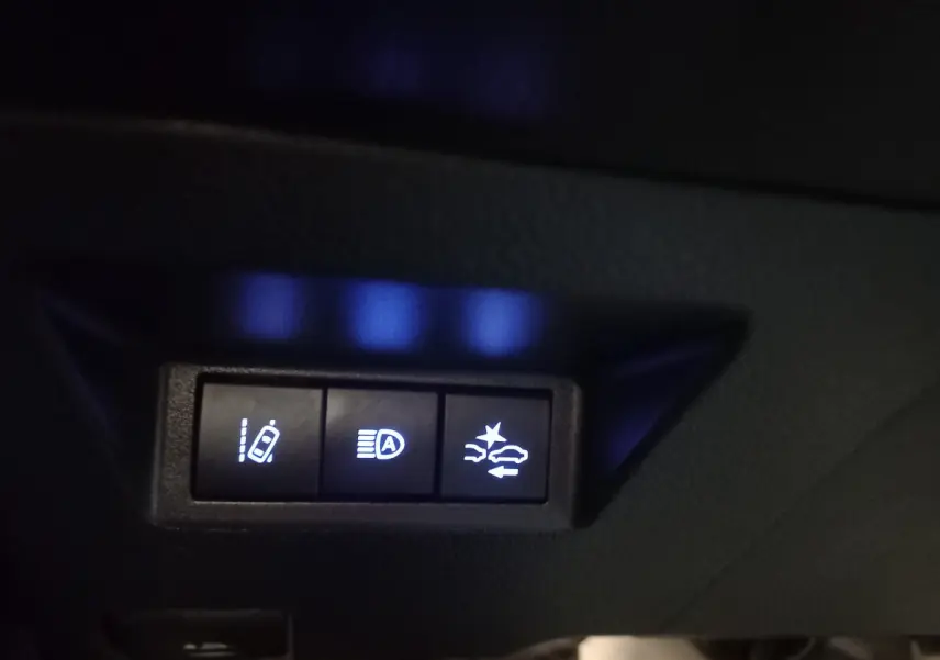 Gros plan sur les boutons de sécurité et assistance au conducteur de la Toyota Yaris noire 2018, éclairage bleu.