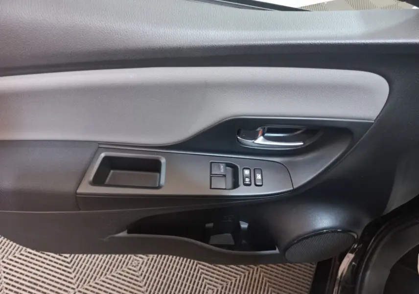 Intérieur côté gauche de la porte d'une Toyota Yaris noire, avec commandes de vitres et poignée chromée visible.