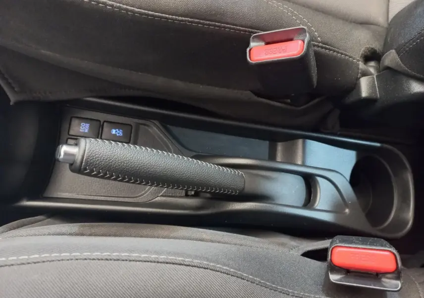 Vue rapprochée de la console centrale noire de la Toyota Yaris 2018, montrant frein à main et boutons Eco Mode et traction.