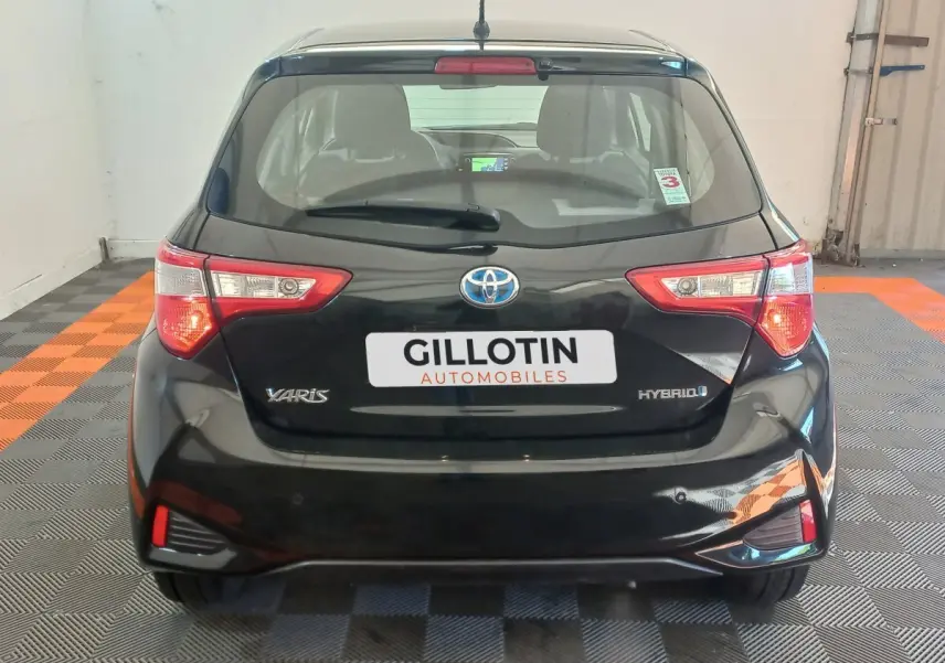 Vue arrière d'une Toyota Yaris noire hybride 2018 avec feux arrière distinctifs et logo Toyota visible.