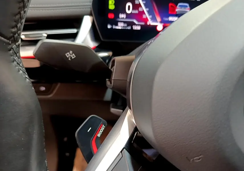 Gros plan sur le volant cuir et alu d’une BMW X1 xDrive23i M Sport 2023, avec palette Boost et tableau de bord numérique.