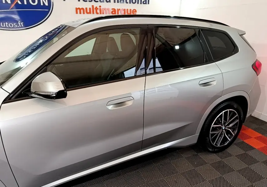 Vue latérale droite d’un BMW X1 gris clair 2023 avec jantes alliage et rétroviseurs électriques noirs.