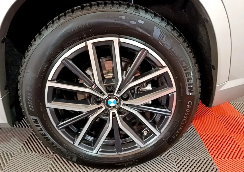 Gros plan sur la roue avant droite d’un BMW X1 gris clair avec jante alliage M Sport et pneu Michelin.