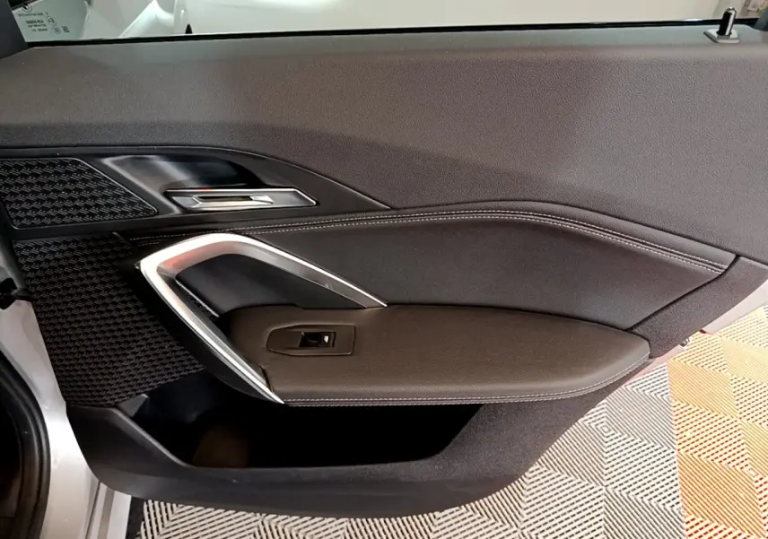 Vue intérieure du panneau de porte côté gauche en cuir noir avec surpiqûres blanches d’un BMW X1 gris clair 2023.