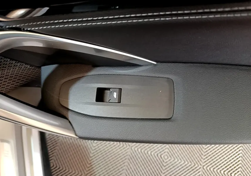 Gros plan sur le bouton de commande de vitre électrique côté conducteur, intérieur noir du BMW X1 gris clair 2023.