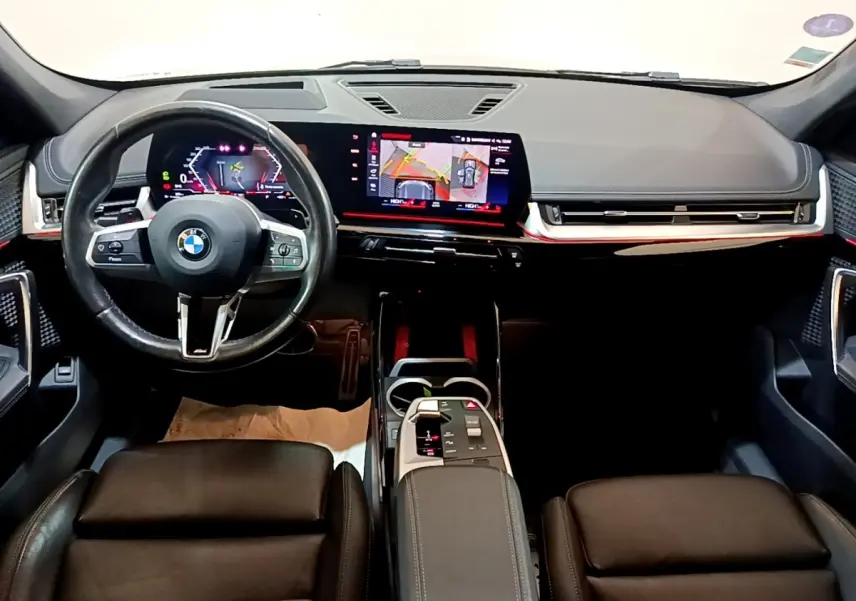 Vue intérieure avant du BMW X1 xDrive23i M Sport 2023, tableau de bord numérique et écran tactile central lumineux.