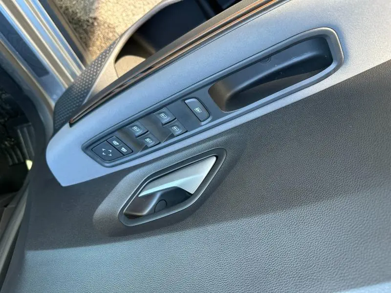 Gros plan sur la porte avant gauche du Dacia Jogger blanc, montrant les commandes des vitres et la poignée intérieure grise.