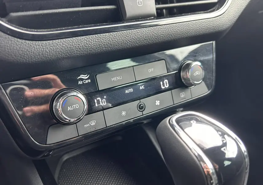 Gros plan sur la console centrale noire du Skoda Scala blanc, montrant la climatisation automatique bi-zone et le levier de vitesses.