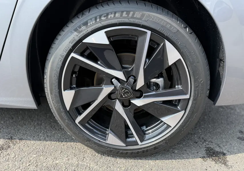 Gros plan sur la jante avant droite en alliage noir et argent du Peugeot 308 gris Artense 2025.
