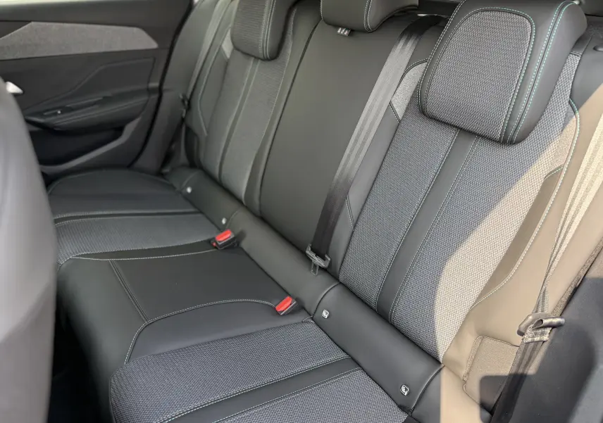 Vue latérale des sièges arrière en cuir et tissu gris avec surpiqûres bleues d'une Peugeot 308 2025.