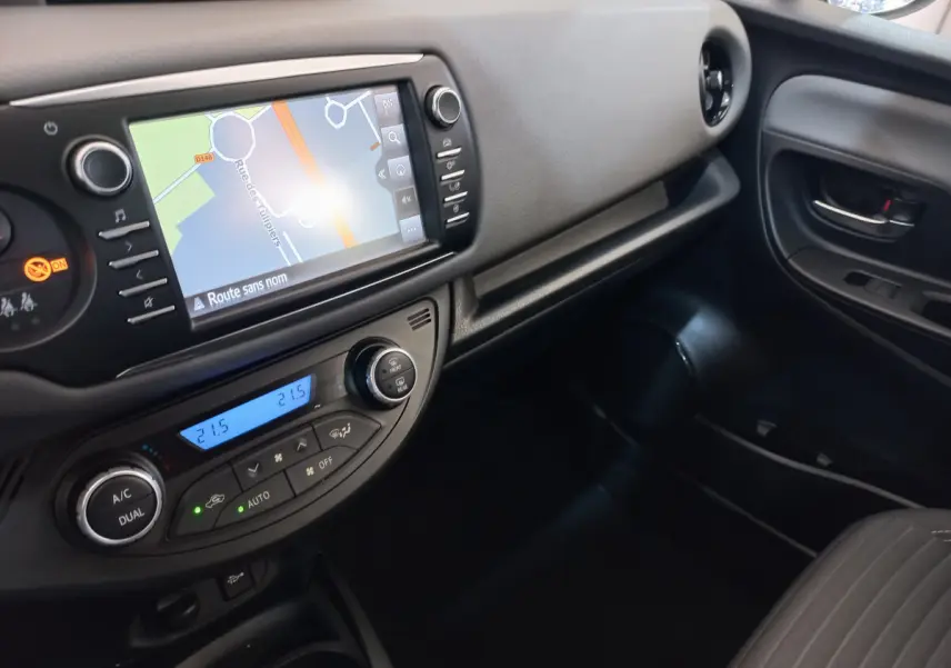 Vue intérieure côté passager de la Toyota Yaris 2019 avec écran tactile de navigation et commande de climatisation digitale.
