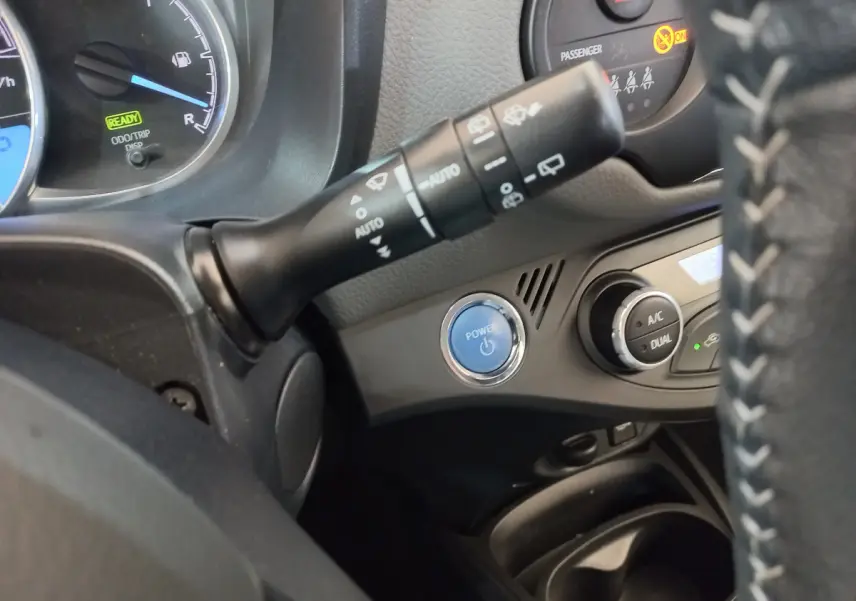 Détail intérieur côté gauche montrant le bouton Power bleu et commandes de climatisation de la Toyota Yaris hybride 2019.