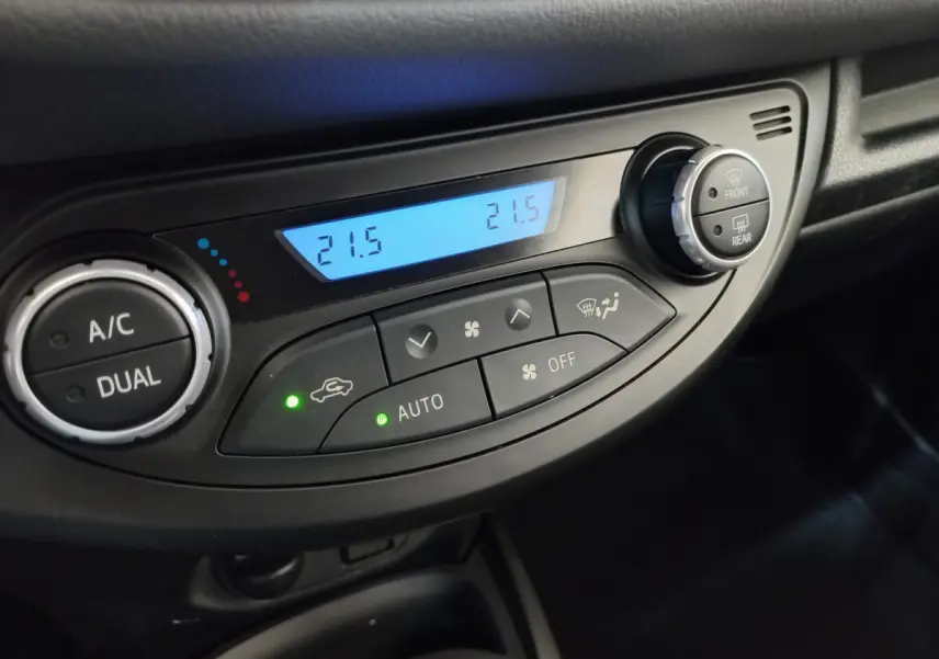 Gros plan sur la commande de climatisation bi-zone avec affichage digital à 21,5°C dans une Toyota Yaris blanche 2019.
