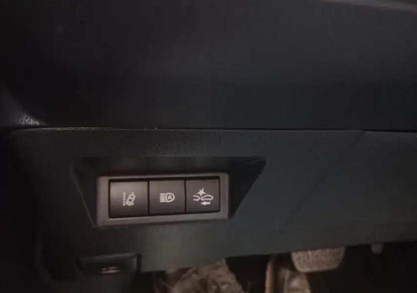 Gros plan sur les commandes d'assistance à la conduite sous le tableau de bord d'une Toyota Yaris blanche hybride 2019.