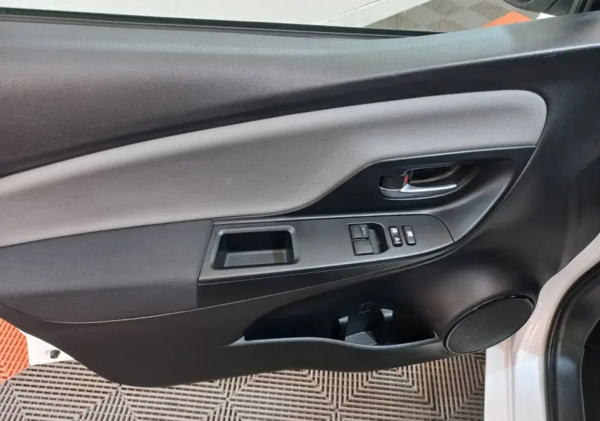 Panneau intérieur de porte côté gauche noir et gris de Toyota Yaris blanche, avec commandes de vitres et poignée chrome.