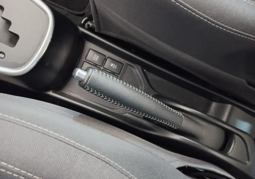 Gros plan sur le frein à main en cuir noir avec surpiqûres blanches dans l'habitacle de la Toyota Yaris hybride 2019.