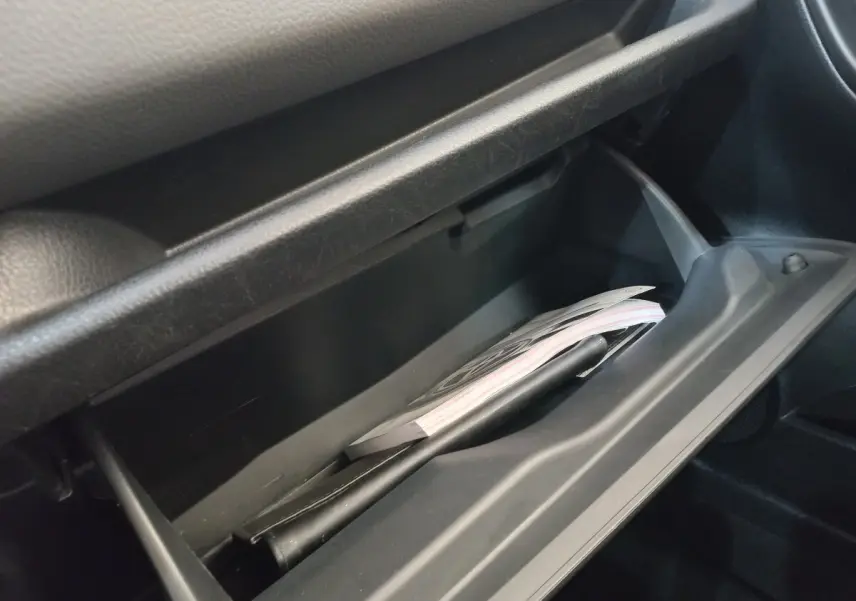 Gros plan sur la boîte à gants ouverte de la Toyota Yaris 1.5 VVT-I Hybride, montrant des documents à l'intérieur.