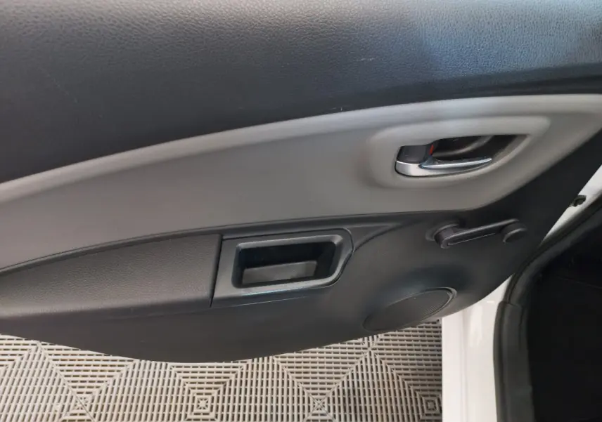 Poignée intérieure et manivelle de vitre côté droit de la porte d'une Toyota Yaris blanche, vue rapprochée.