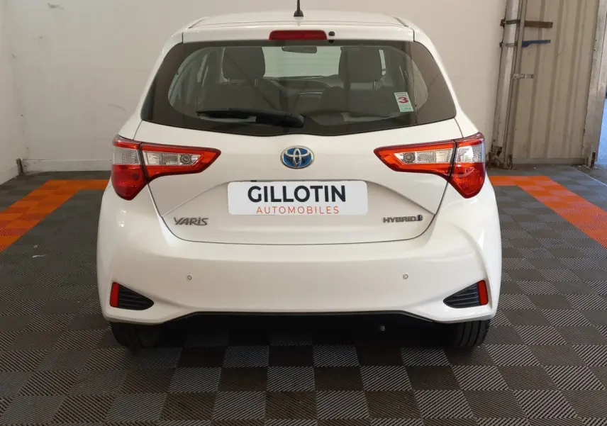 Vue arrière d'une Toyota Yaris blanche hybride 2019 avec feux arrière distinctifs et logo Toyota visible.