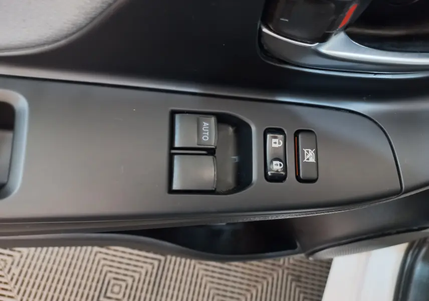 Gros plan sur les commandes de lève-vitres et verrouillage côté conducteur d'une Toyota Yaris blanche 2019.