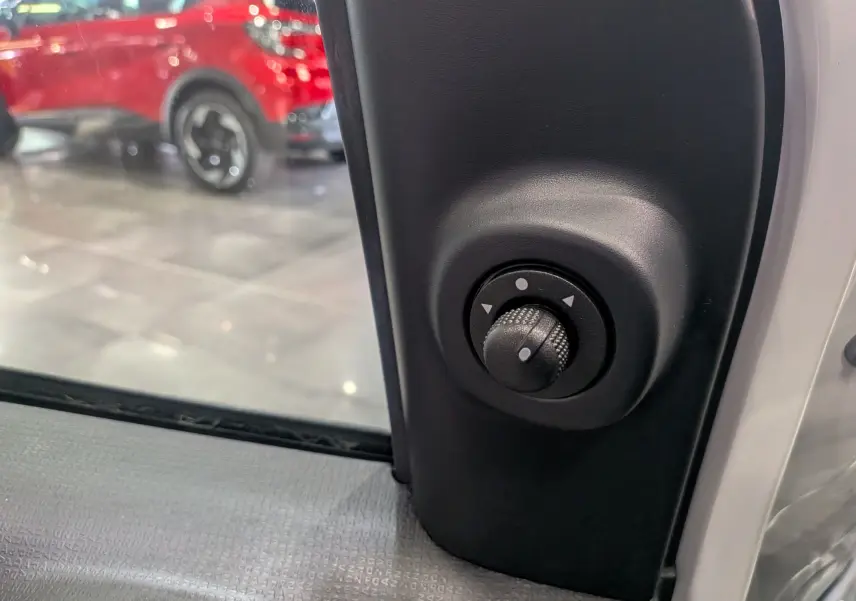 Gros plan sur le réglage manuel du rétroviseur côté gauche d'une Fiat Panda 1.0 hybride blanc Gelato.