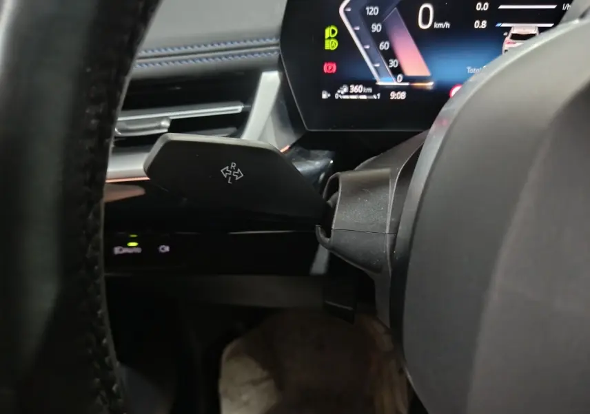 Gros plan sur le combiné d'instruments digital et levier de clignotant dans l'habitacle noir du BMW X1 hybride 2024.