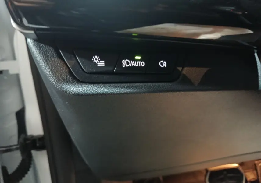 Détail des commandes d’éclairage avec bouton auto allumé sur BMW X1 blanc, vue intérieure côté conducteur.