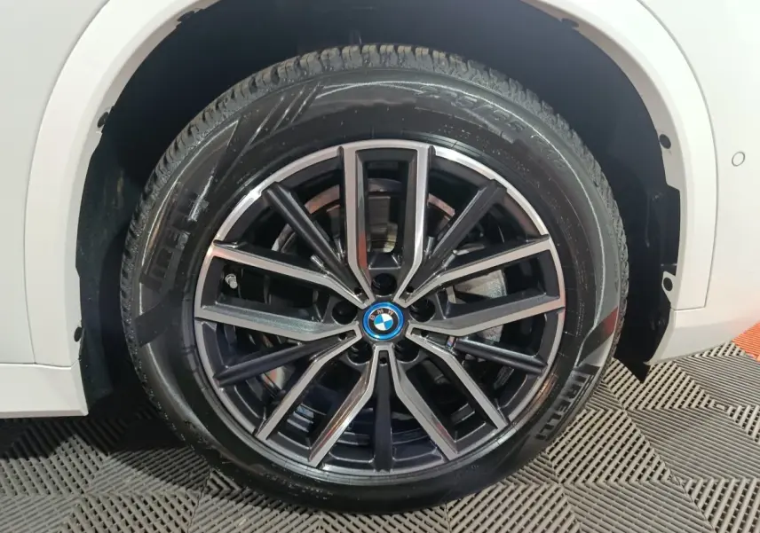Gros plan sur la roue avant droite noire et argentée du BMW X1 blanc xDrive25e M Sport 2024.