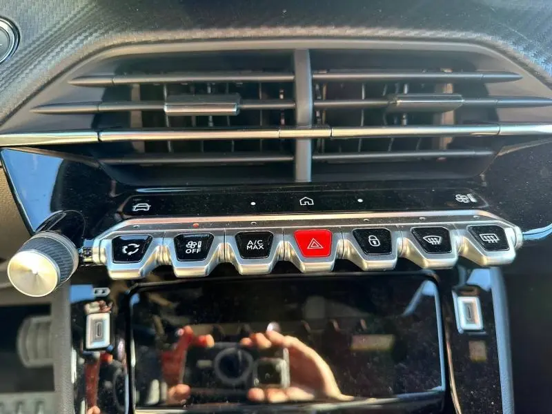 Gros plan sur la console centrale de la Peugeot 2008 Bleu Obsession 2025, montrant les boutons de commande et les aérateurs.