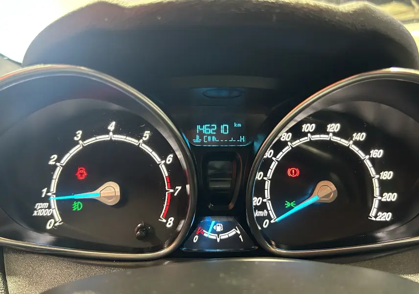 Vue rapprochée du tableau de bord de la Ford Fiesta blanche, affichant 146210 km au compteur.