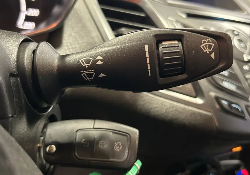 Gros plan sur la manette de commande des essuie-glaces dans l’habitacle d’une Ford Fiesta blanche de 2015.