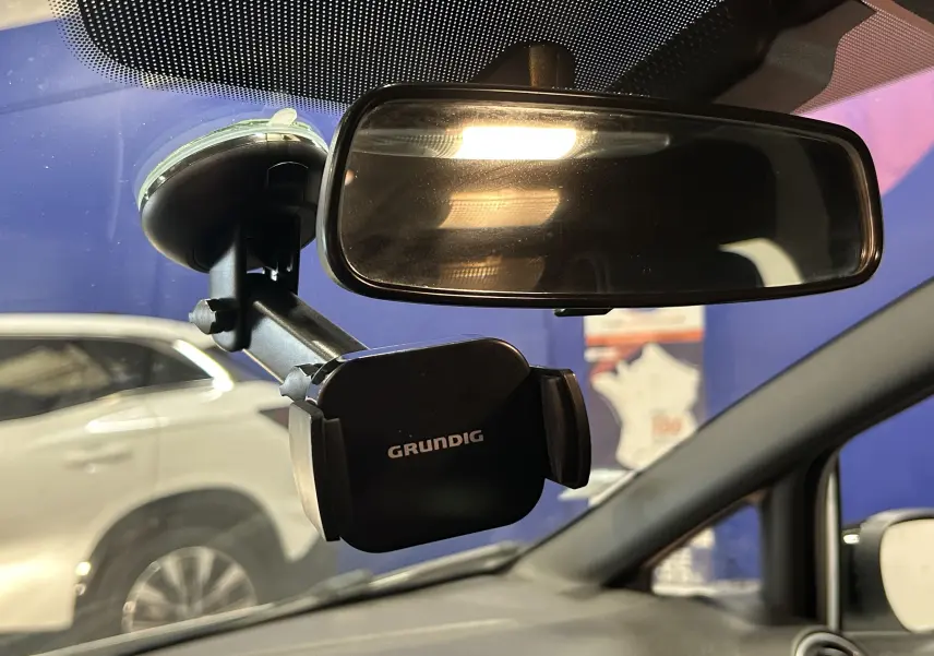 Vue intérieure du rétroviseur central et support téléphone Grundig fixé sur le pare-brise d’une Ford Fiesta blanche, côté droit visible.