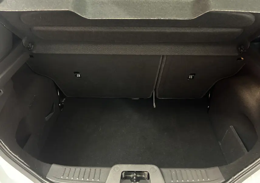 Coffre ouvert vu de l'arrière d'une Ford Fiesta blanche, montrant un espace de chargement propre et vide.