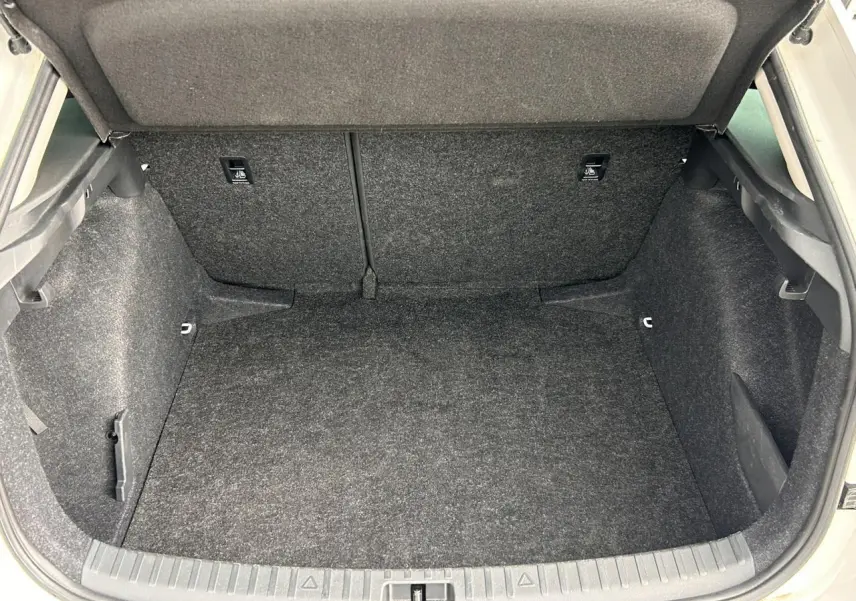 Coffre ouvert vu de l'arrière d'une Skoda Scala TSI 116 DSG7 blanc Candy, espace de rangement vide et tapissé gris.