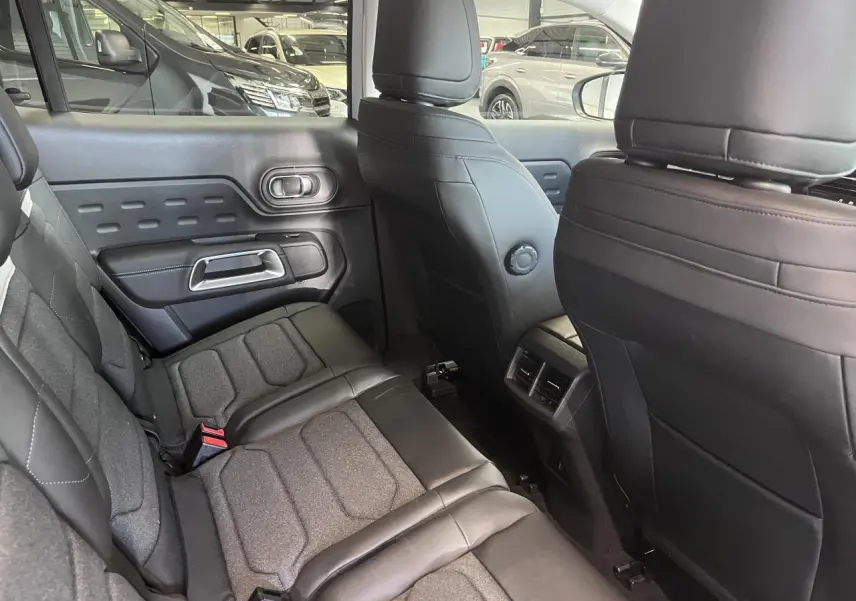Vue intérieure arrière côté gauche du Citroën C5 Aircross 2025, sièges tissu et cuir noir avec surpiqûres.