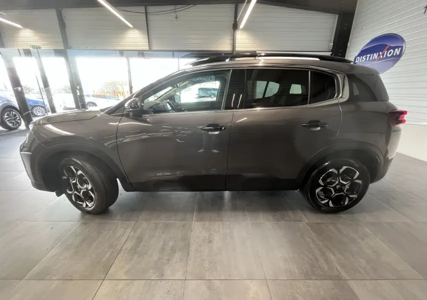 Vue latérale droite d'un Citroën C5 Aircross gris platinium avec jantes alliage 18'' bicolores en showroom.