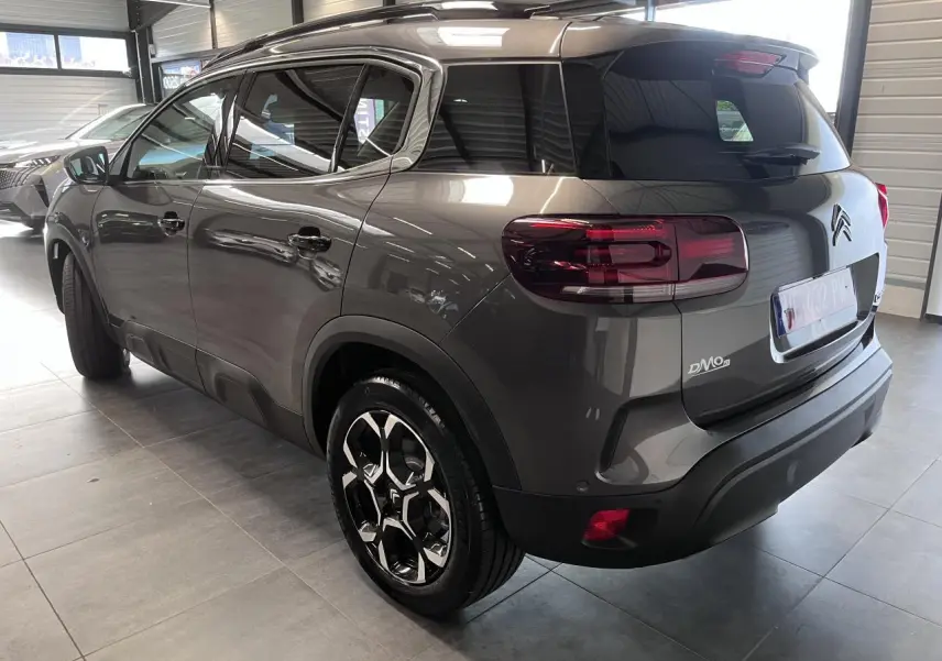 Vue 3/4 arrière droite d'un Citroën C5 Aircross gris platinium avec jantes alliage bi-ton et vitres surteintées.