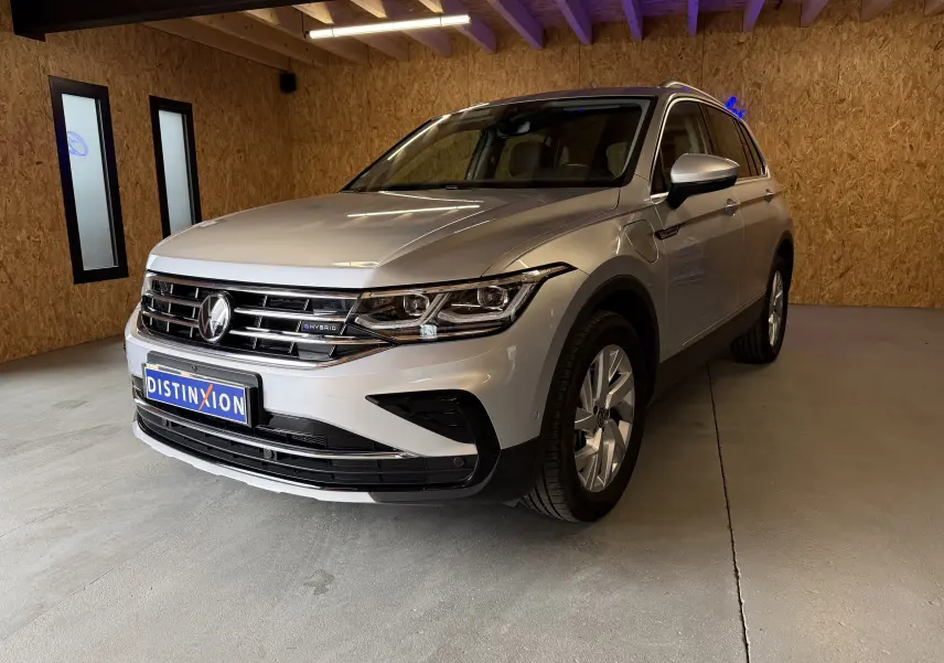 Vue frontale d'un Volkswagen Tiguan gris clair 1.4 e-Hybrid avec calandre chromée et logo distinctif e-Hybrid visible.