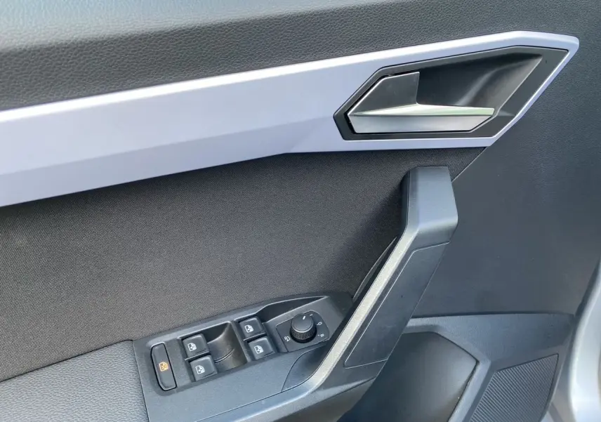 Gros plan sur la porte côté conducteur du SEAT Arona gris silver avec garniture noire et commandes électriques.
