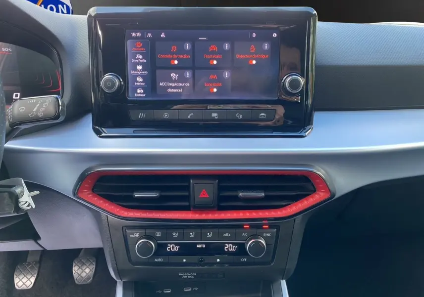 Tableau de bord du SEAT Arona 2024 avec écran tactile, climatisation bi-zone et cadre d’aération rouge vif.