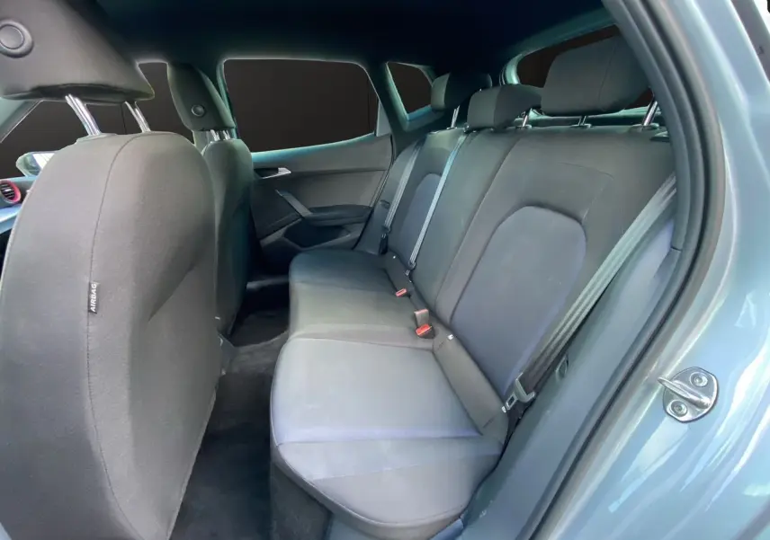 Vue intérieure côté droit sur les sièges arrière noirs en tissu du SEAT Arona 2024 gris silver avec porte ouverte.