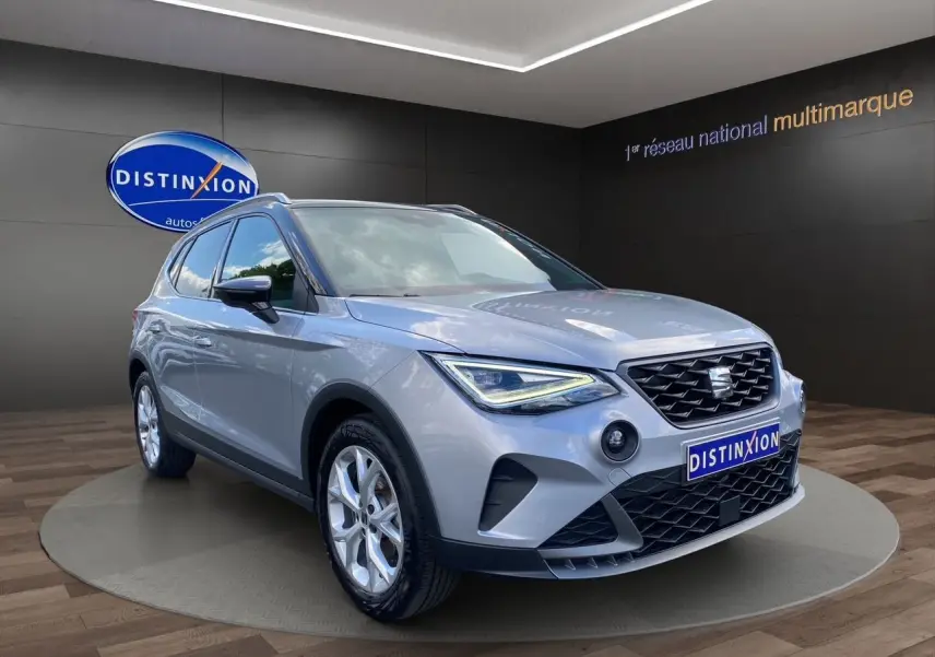 SEAT Arona gris silver avec toit noir, vue 3/4 avant droit, jantes alu 17 pouces et feux LED allumés.