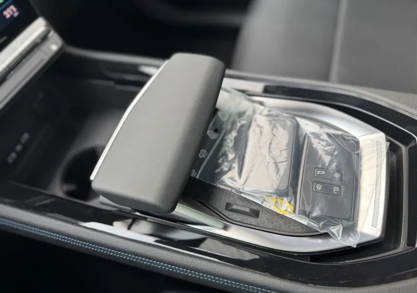 Gros plan sur la console centrale du Renault Austral 2025, mettant en valeur le repose-bras et deux clés sous plastique.