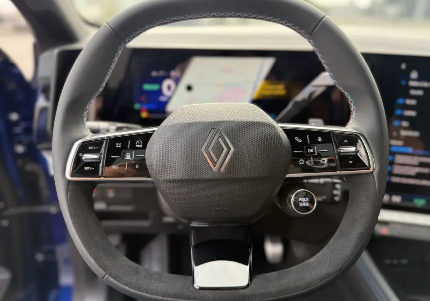 Gros plan sur le volant cuir du Renault Austral 2025, avec commandes intégrées et logo Renault au centre.