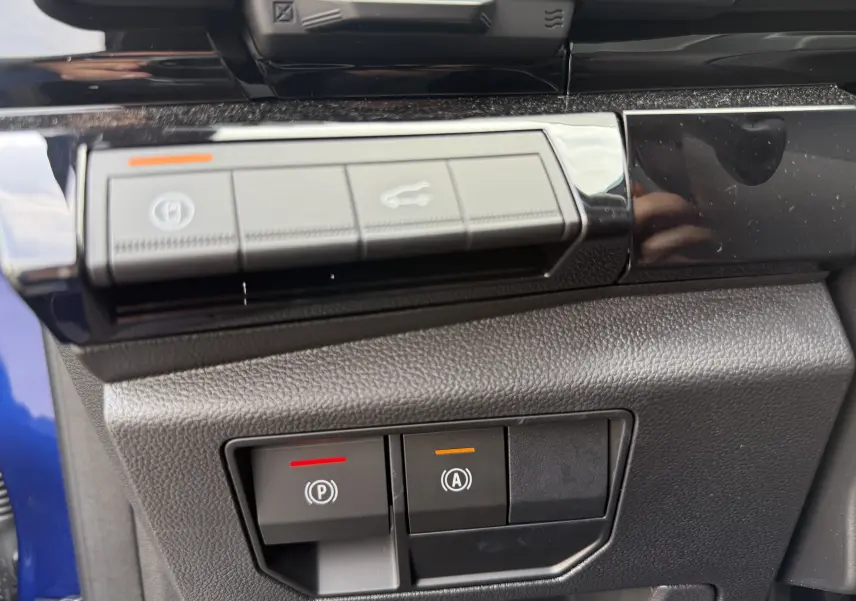 Gros plan sur les commandes de frein à main et assistance au démarrage du Renault Austral 2025 bleu Iron avec toit noir.