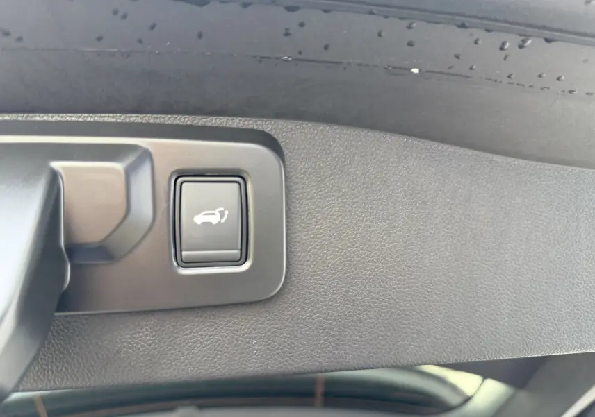 Bouton d'ouverture électrique du coffre sur le hayon intérieur d'un Renault Austral bleu Iron toit noir 2025.