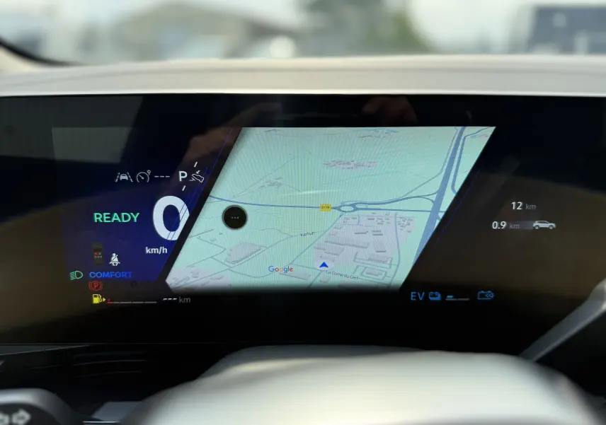 Tableau de bord numérique du Renault Austral 2025 avec affichage de la navigation et indicateurs de conduite en mode hybride.